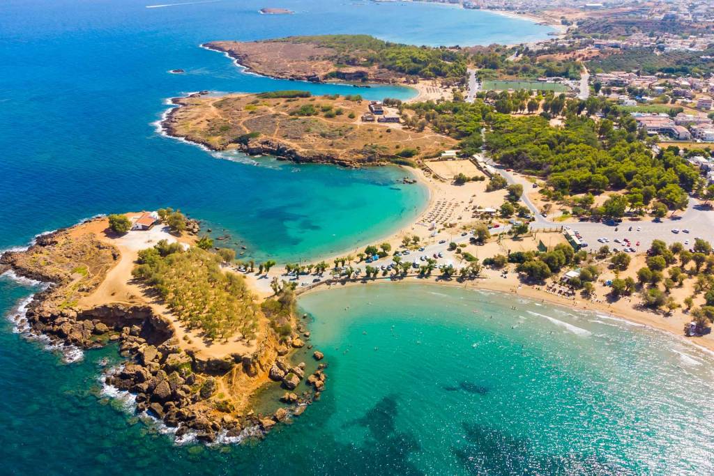 A seaside chapel, umbrellas, and sunbeds in Agii Apostoli Beach.