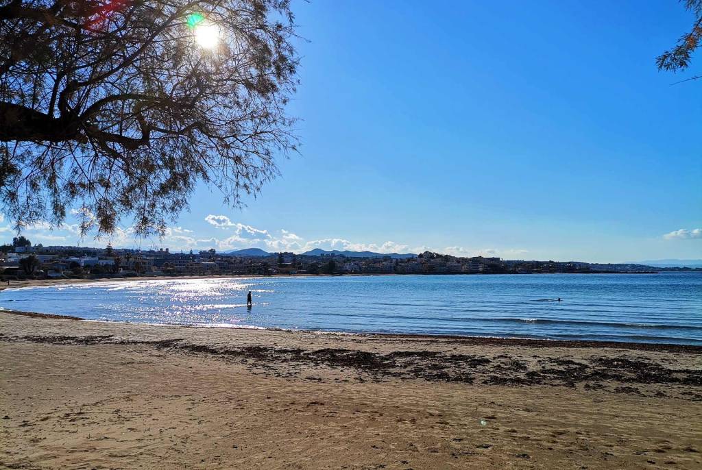 The sun shines above the sandy Agii Apostoli Beach.
