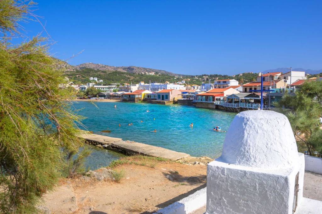 Traditional houses and people swimming in Almyrida Beach.