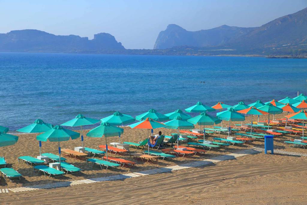 A woman sits on a sunbed in the organized Falassarna Beach.