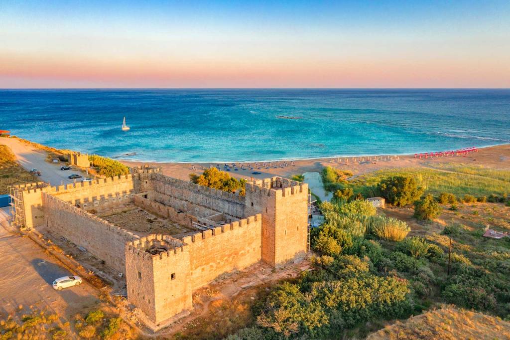 A catamaran is sailing at sunset in Frangokastello Beach, overlooking the Castle.