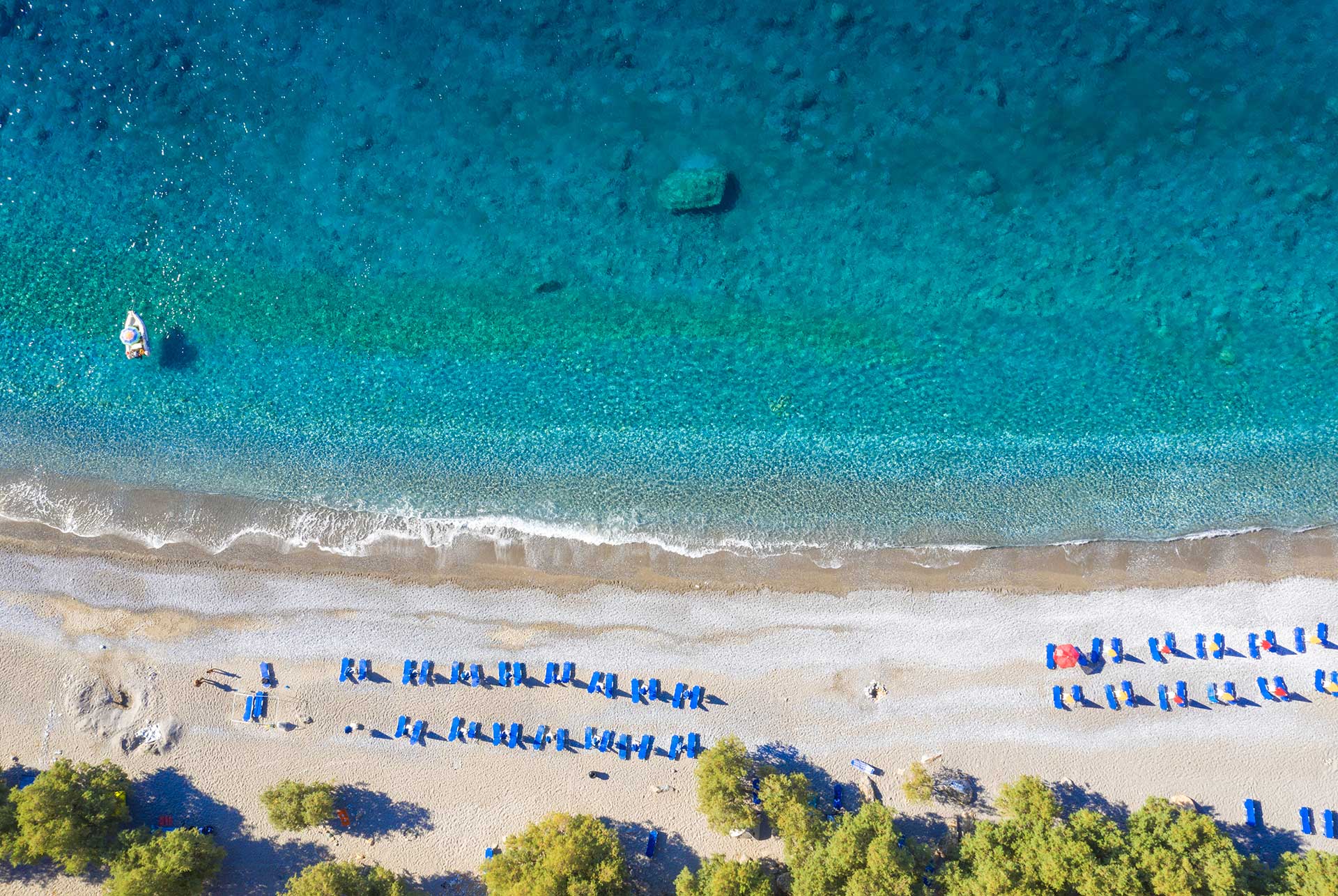 Aerial view of the sunbeds and umbrellas in Glyka Nera remote beach in South Chania.