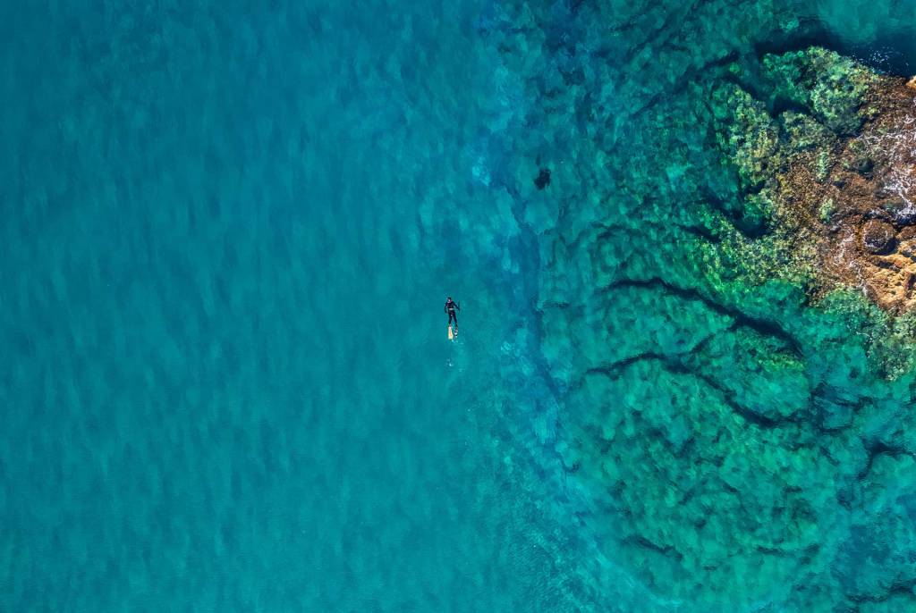 A man swims in the waters of Kalathas Beach.
