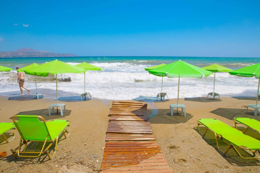 The sandy Kalyves Beach with yellow umbrellas and sunbeds.