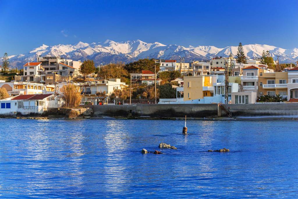 Houses and apartments in Galatas Village overlook the sea and the snow-covered mountains.