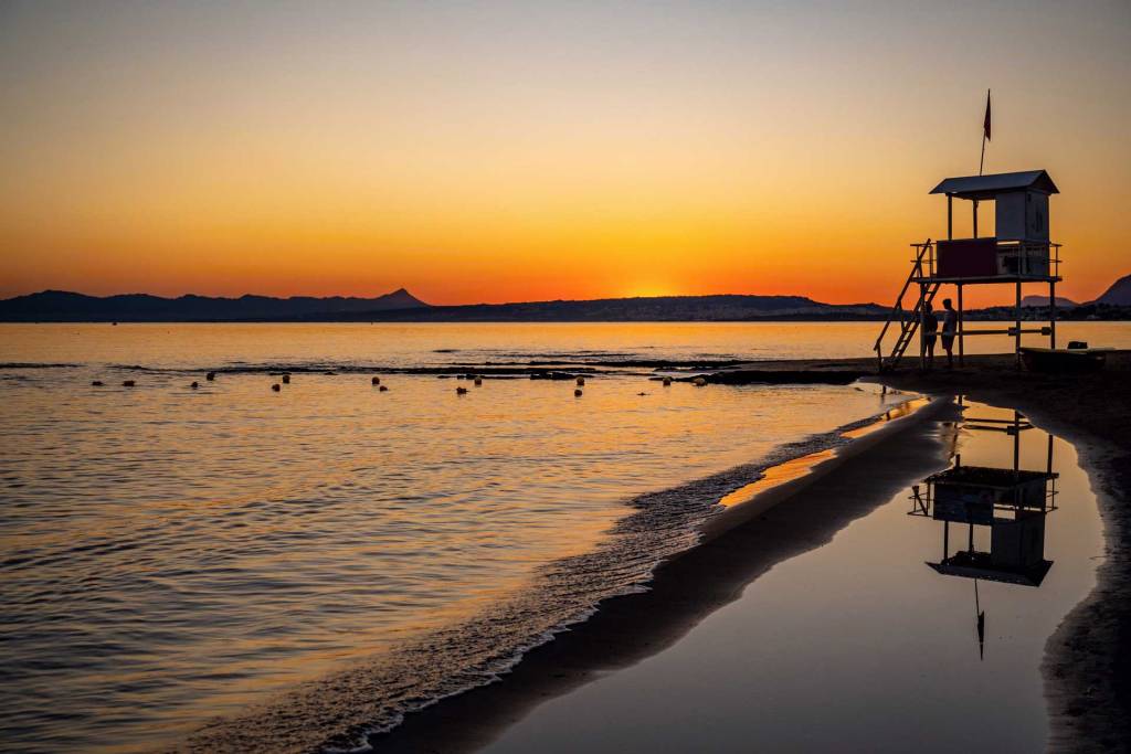 Sunset view of Stalos Beach and a lifeguard tower.