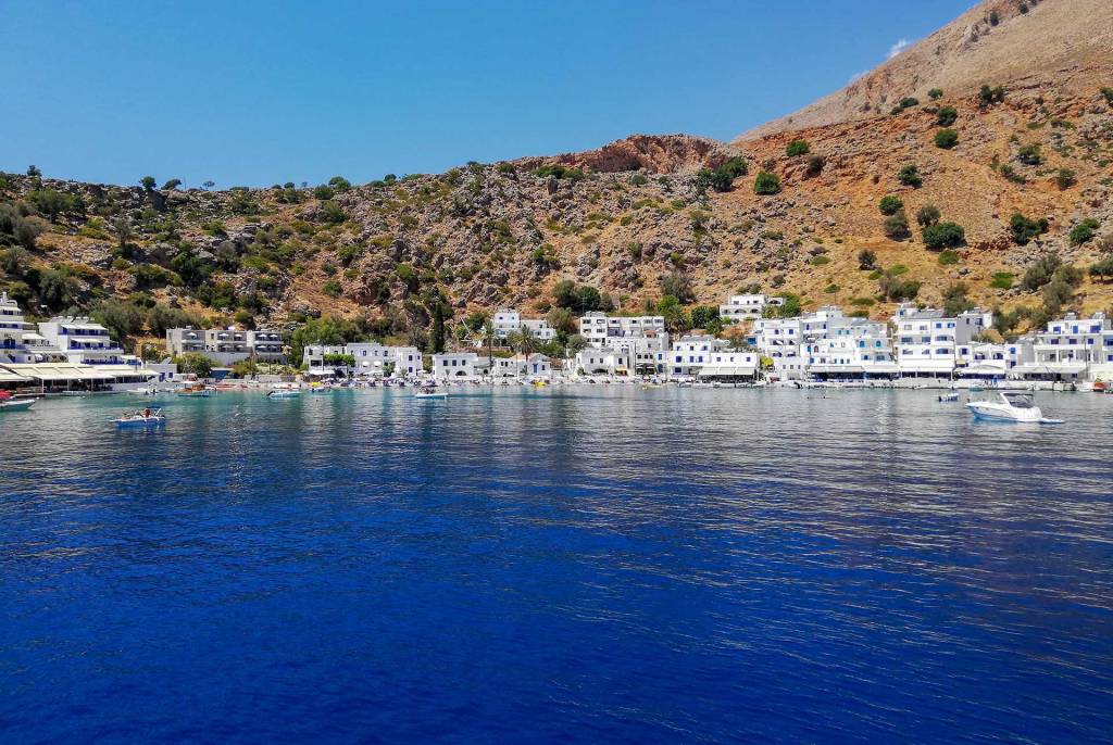 Private boats, traditional houses, and hotels in Loutro Beach.