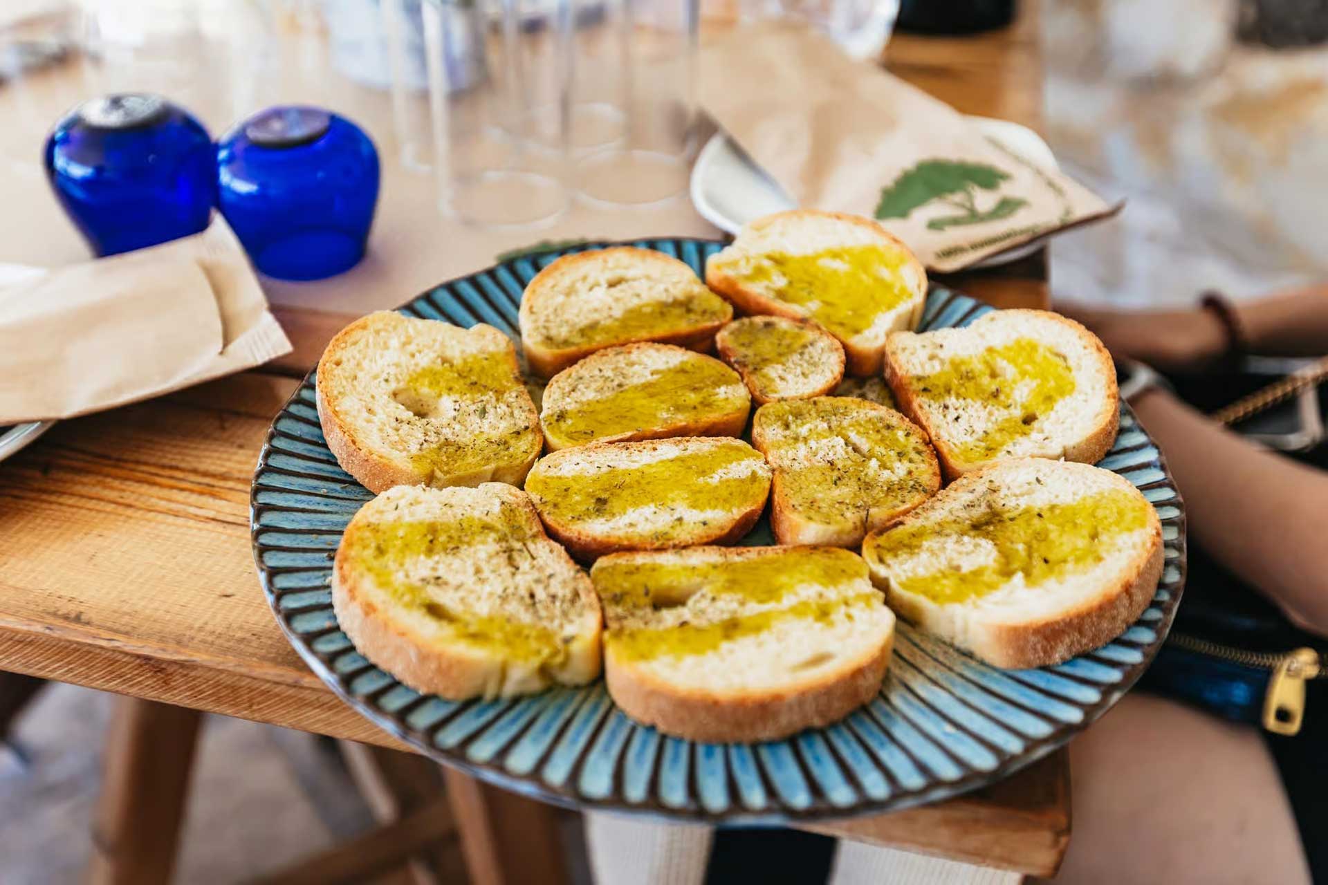 A plate with slices of bread, olive oil, and oregano.