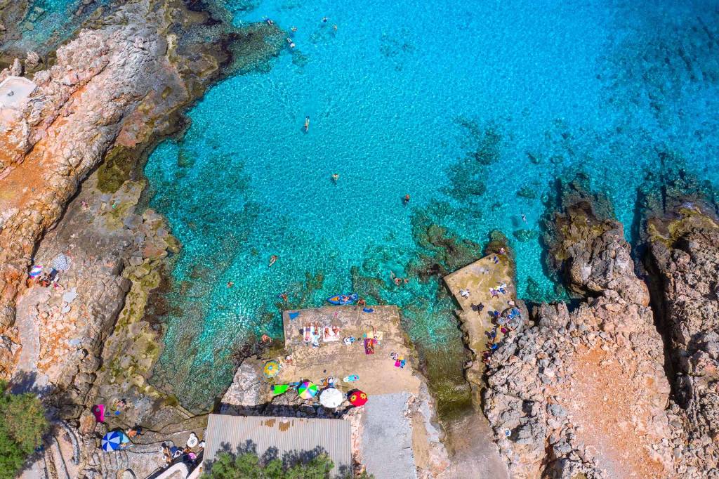 Tourists sunbathing and swimming in Ombros Gialos Beach.