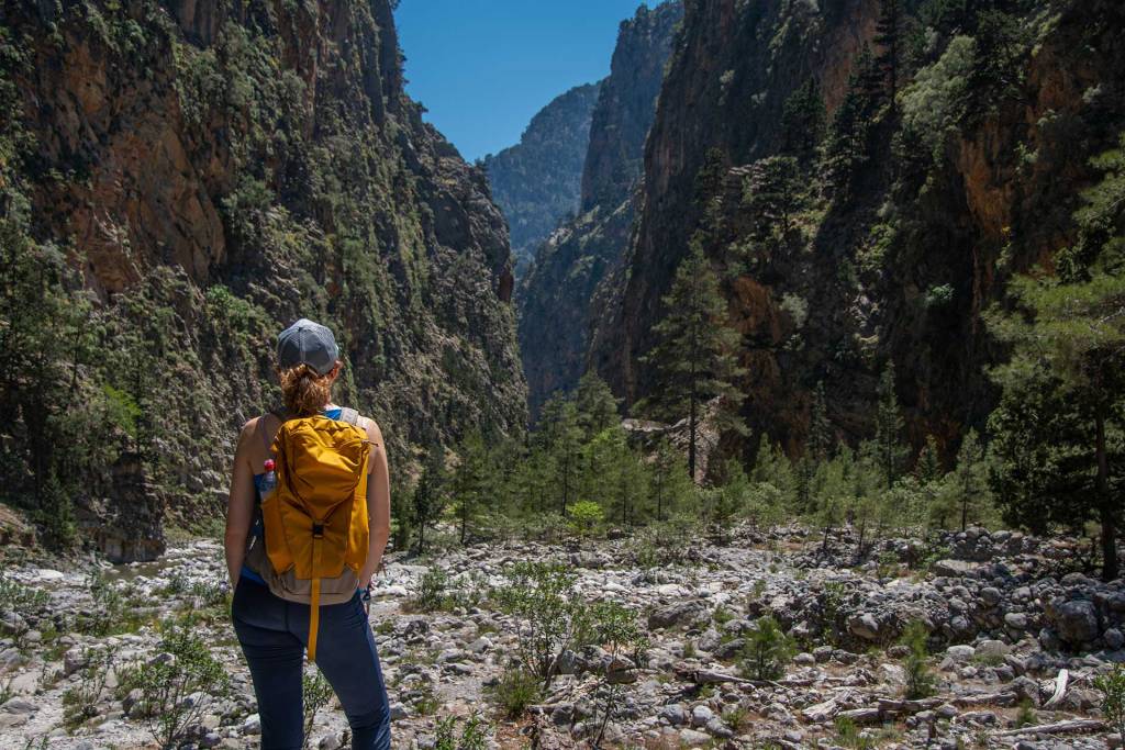A hider with a backpack and a hat admires the view of Samaria Gorge.