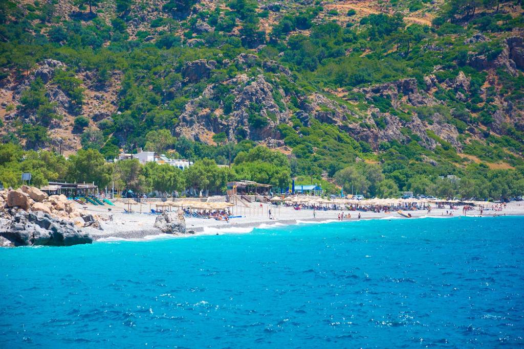 Sunbeds, umbrellas, and seaside cafes in Sougia Beach.
