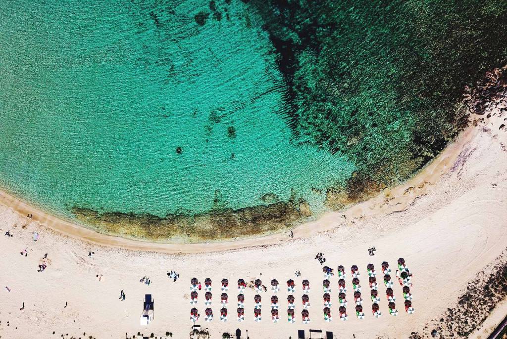 Aerial view of the turquoise waters, sandy coast, and sunbeds in Stavros Beach.