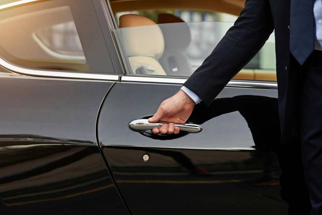 VIP transportation services provided by a driver opening the door of a luxurious car.