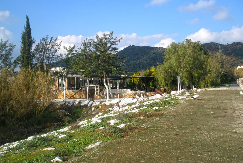 A small cafe next to the lake of Agia Village, surrounded by lush vegetation.