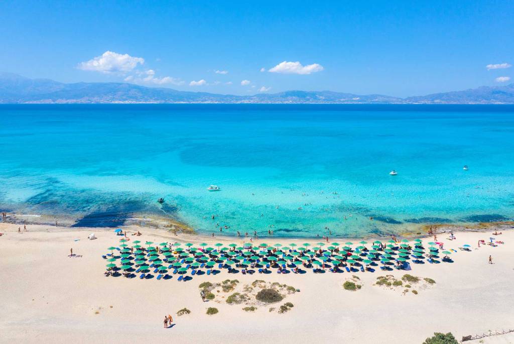 The turquoise waters, sunbeds, and umbrellas of the sandy Chrissi Beach.
