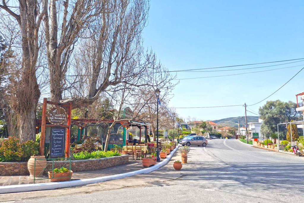 The small square of Kandanos Village in Chania and the Platia Tavern surrounded by trees, next to the road.