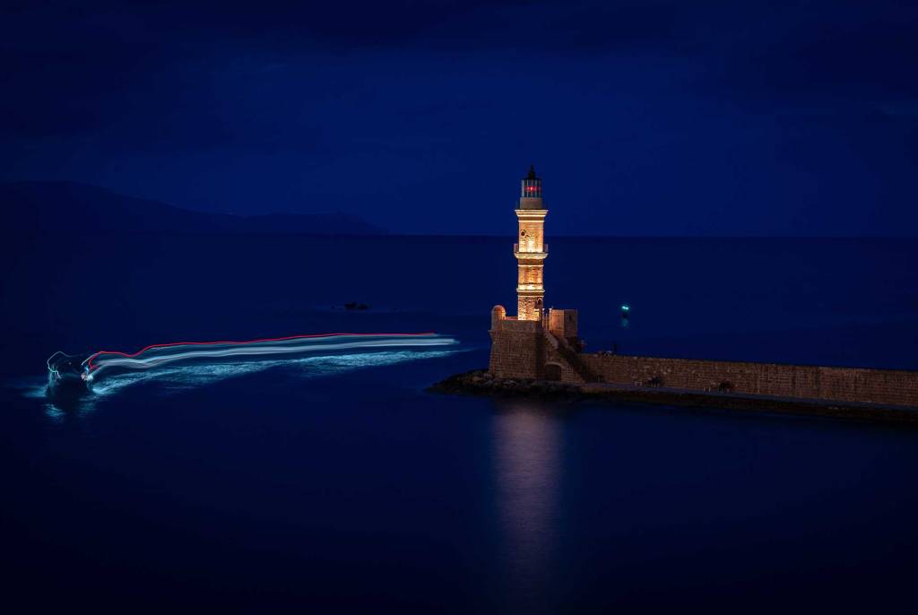 A boat by the Egyptian Lighthouse of Chania at night.