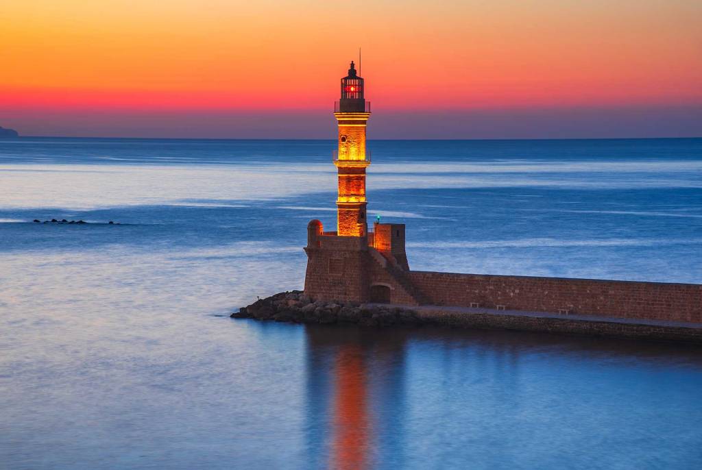 Sunset view of the iconic lighthouse of Chania Old Harbor.