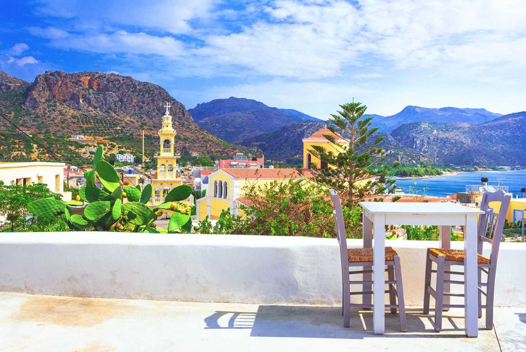 A table and two chairs with a view of Paleochora's main church.