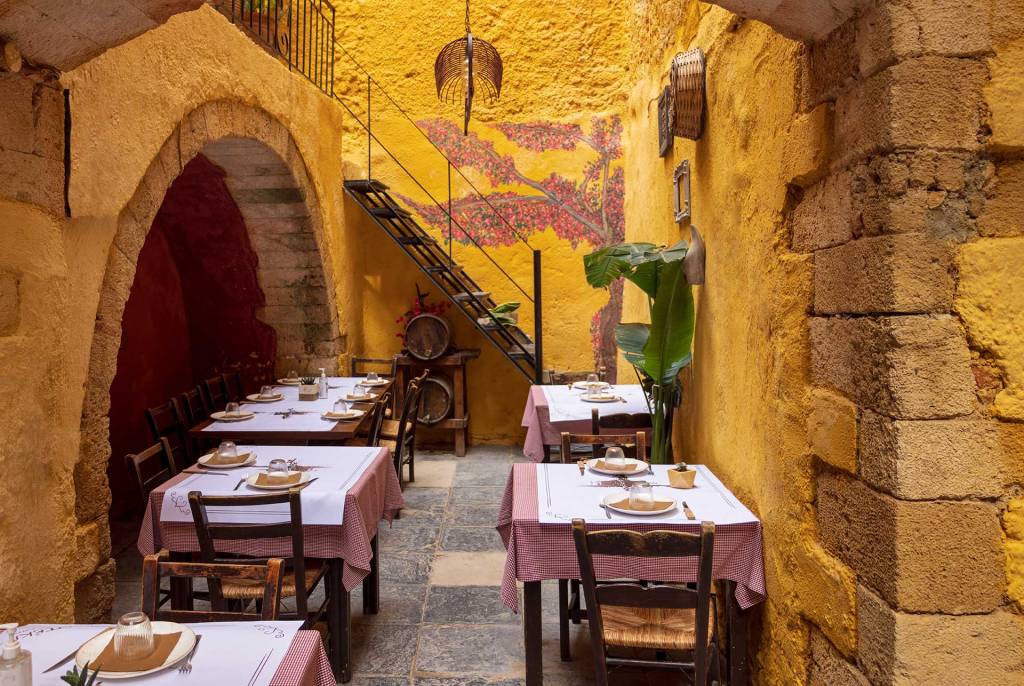 The yellow stone walls and the small tables and chairs of the Ela Tavern in Chania Old Town.