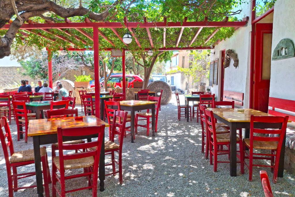 The garden and red chairs and tables of the small, picturesque School tavern in Anidri Village (Chania).