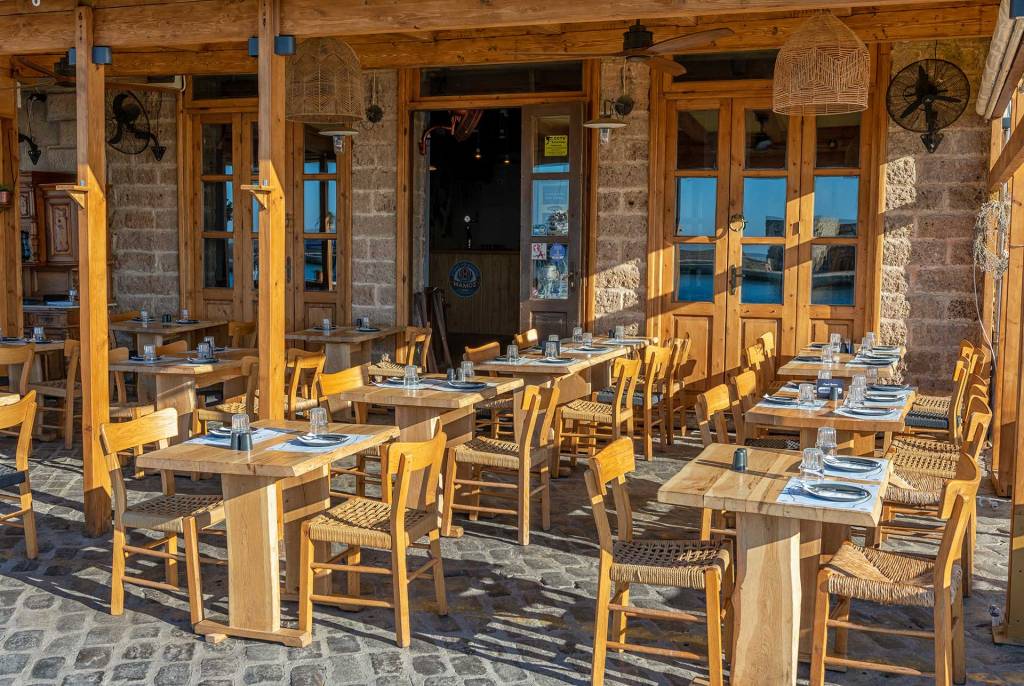 The wooden tables and entrance of the picturesque restaurant Ta Chalkina in Chania Old Harbor.