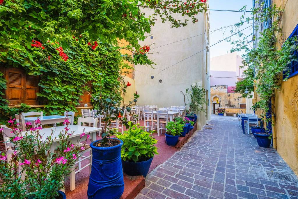 The picturesque yard with the tables of the Well of the Turk Tavern in Chania Old Town, surrounded by trees.