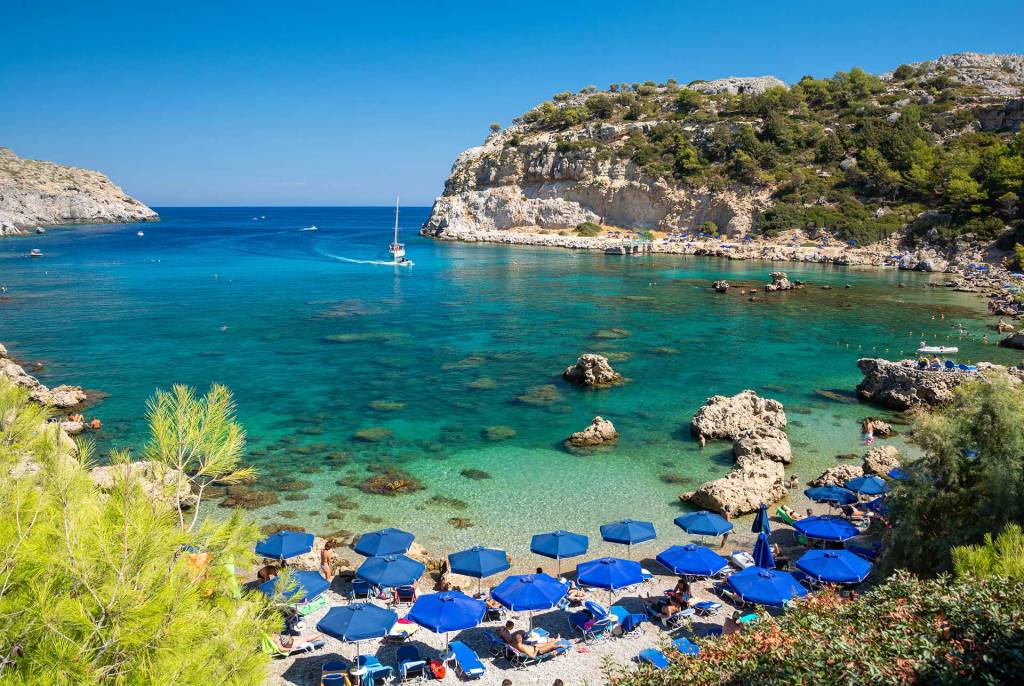 Sunbeds and umbrellas in the beach of Anthony Quinn in Rhodes.