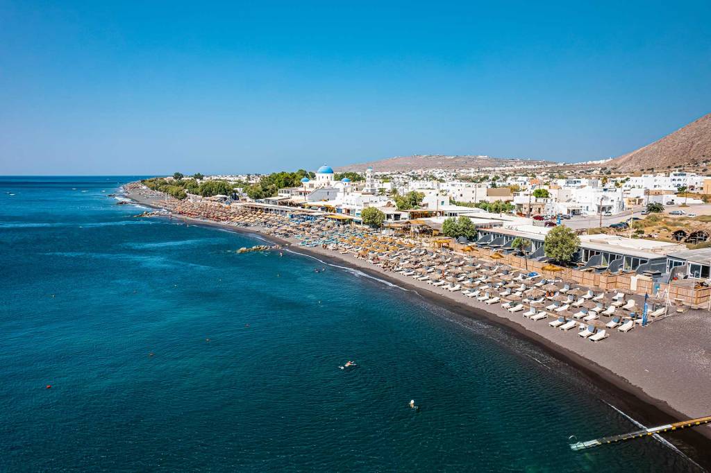 Sunbeds and umbrellas on the organized Perissa Beach, on Santorini Island.