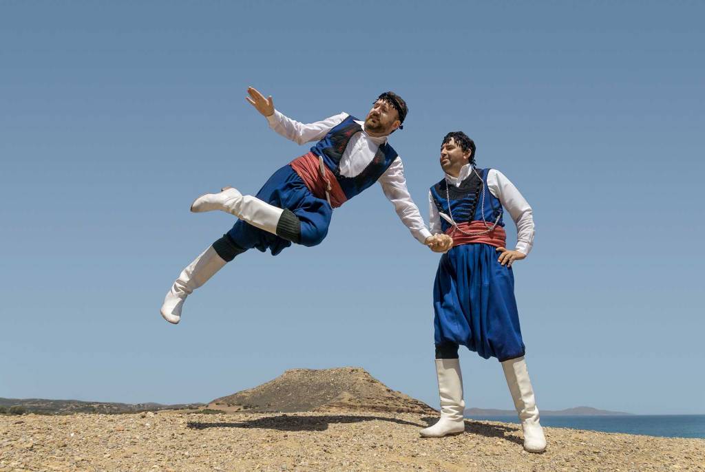 Two male dancers dressed in folk costumes dancing pentozali in Crete.
