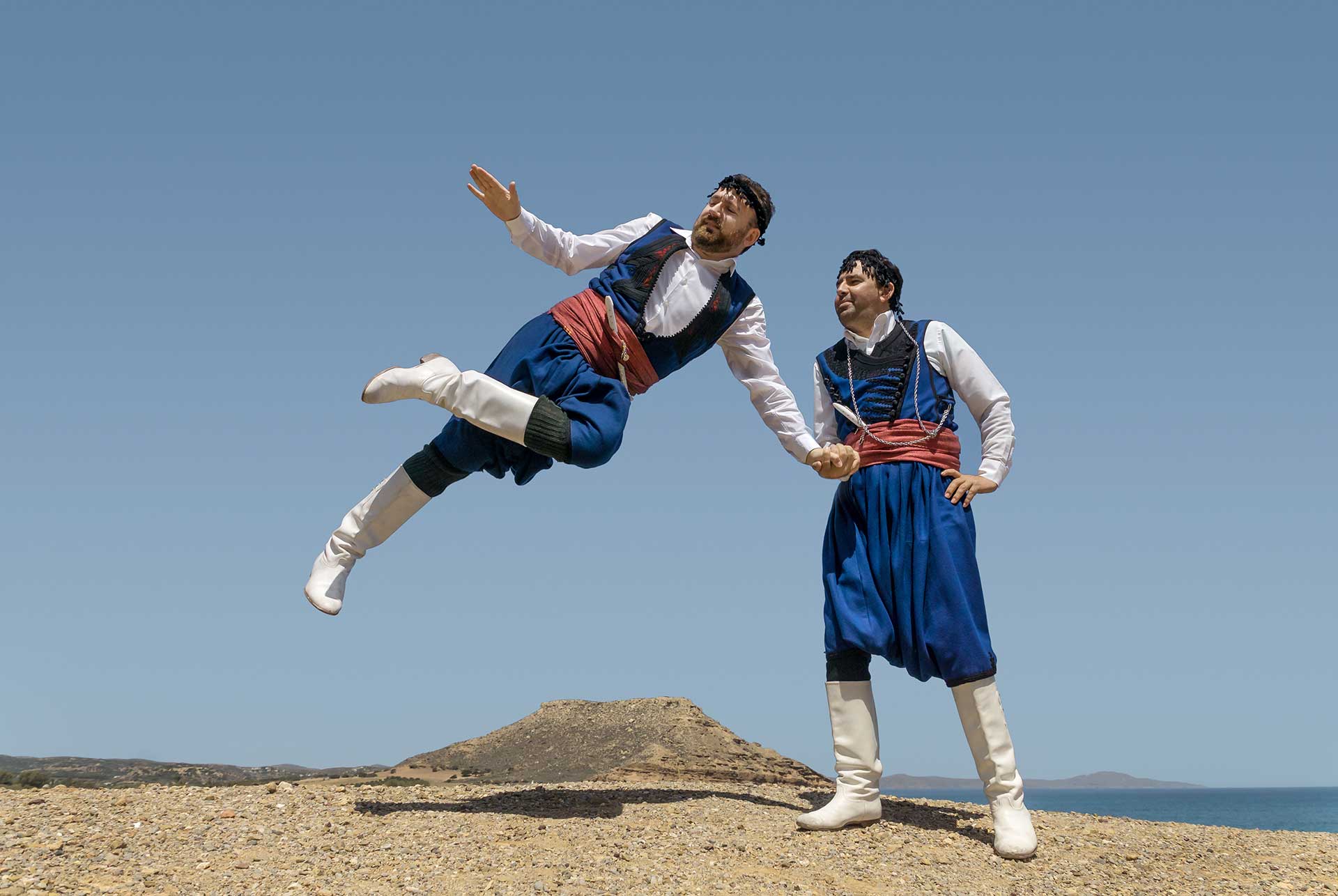 Two male dancers dressed in folk costumes dancing pentozali in Crete.