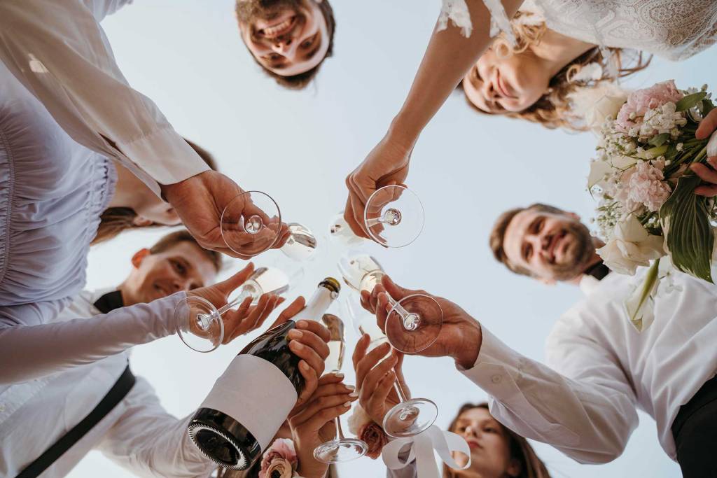 Friends of the groom and bride making a toast while drinking champagne in a circle.