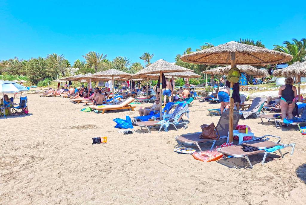 People relaxing in their sunbeds and umbrellas on Grammeno Beach.