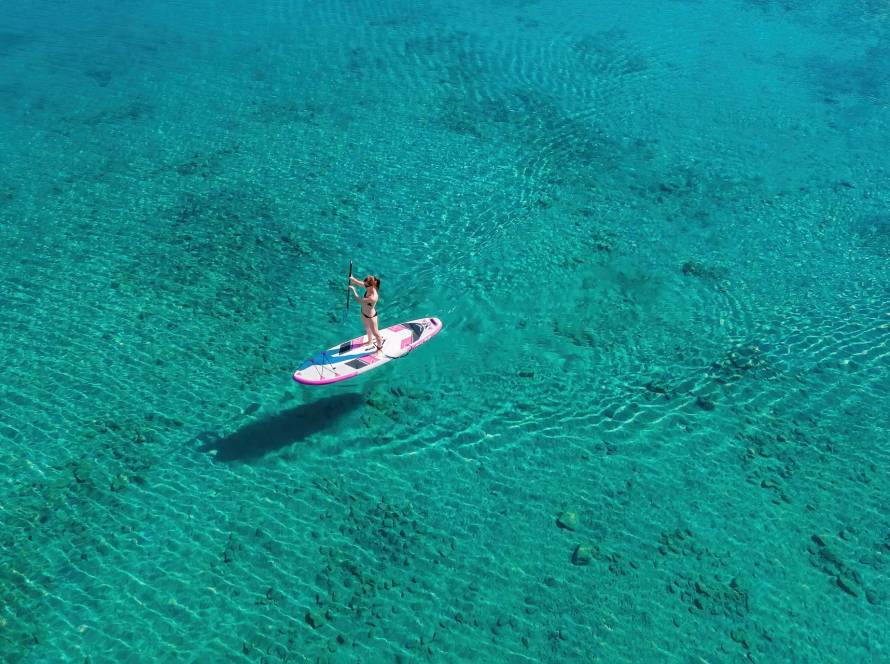 A girl on a SUP board enjoying one one of the best summer experiences around Chania.