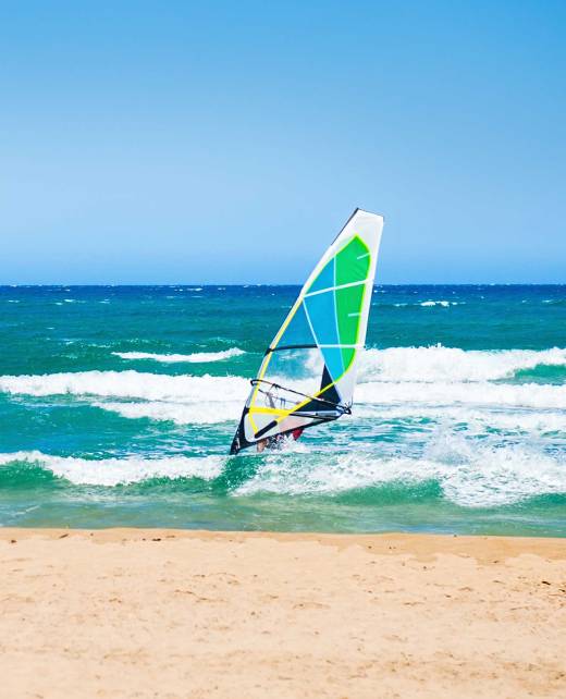 A male windsurfer on a sandy beach in Chania.