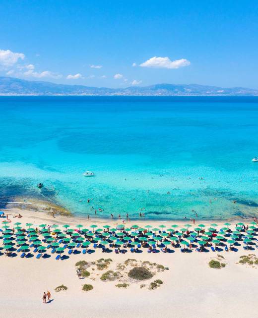 The turquoise waters, sunbeds, and umbrellas of the sandy Chrissi Beach.