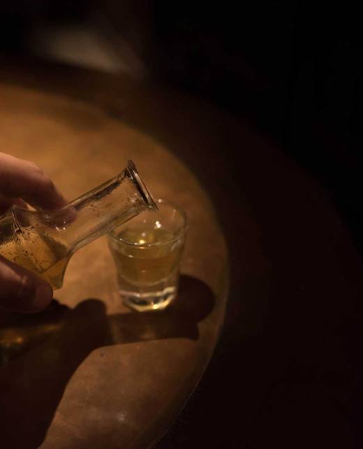A man pours Cretan Raki (Tsikoudia) into a small glass.