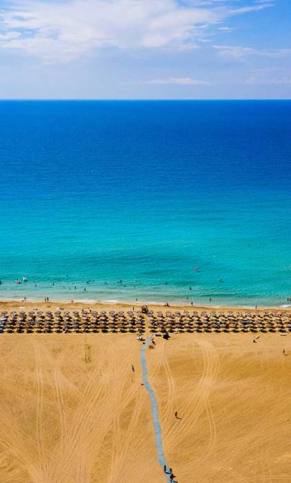 A long coast with sunbeds and umbrellas in Falassarna Beach.