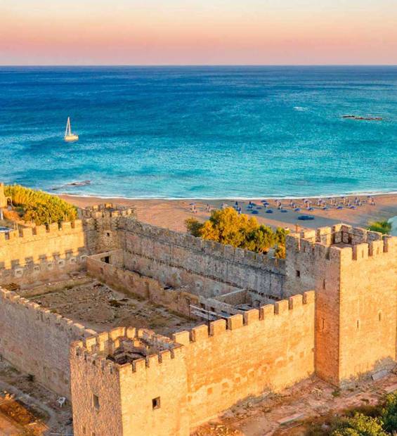 A catamaran sails in the waters of Frangokastello Beach overlooking the Castle.