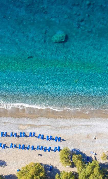 Aerial view of the sunbeds and umbrellas in Glyka Nera remote beach in South Chania.