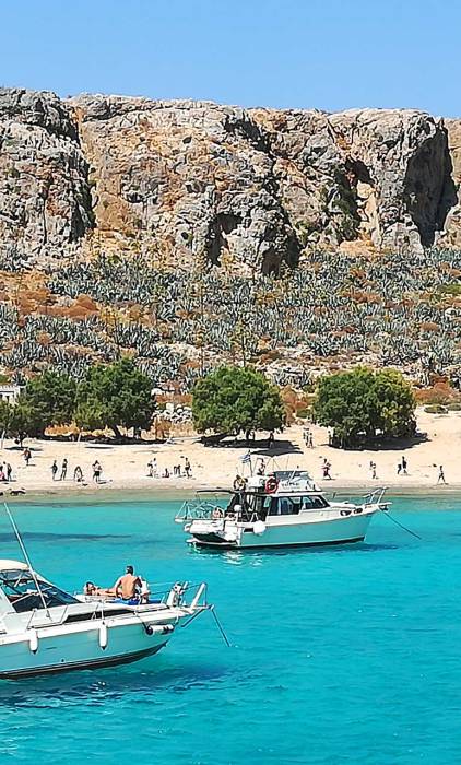 Catamarans and small boats in the waters of Gramvousa Beach.