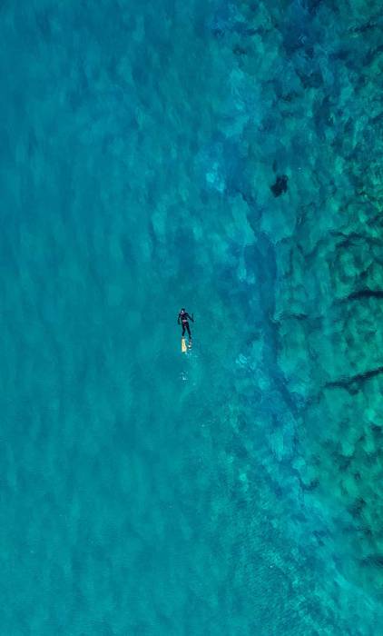 A man swims in the waters of Kalathas Beach.