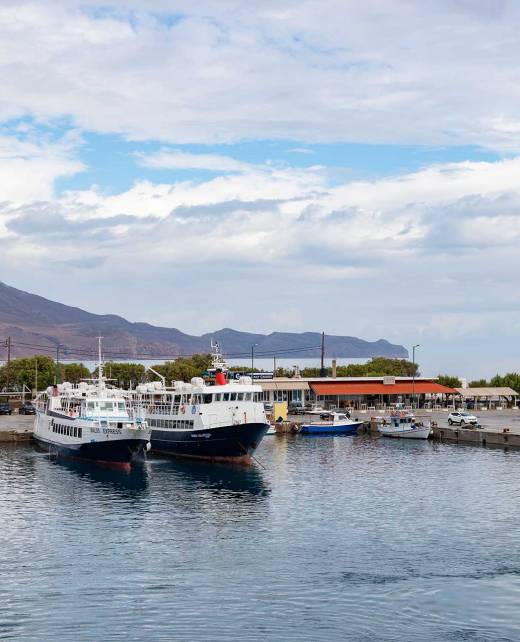 Two ships and some small boats in Kissamos Port (Chania), close to the parking area providing mountain and sea views.