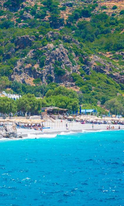 Sunbeds, umbrellas, and seaside cafes in Sougia Beach.