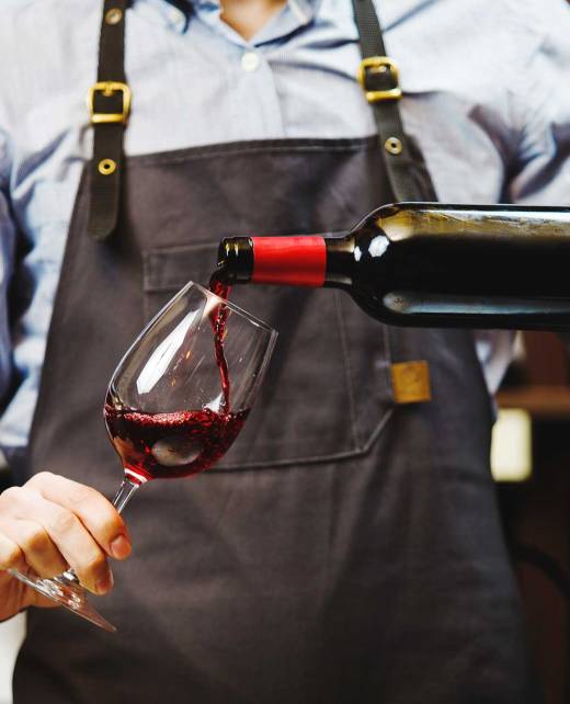 A man pours red wine into a glass.